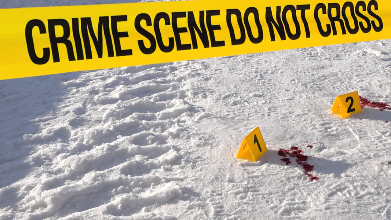 Cinematic move past yellow barrier reveals numbered markers and red paint spatter on bright snowy roadway