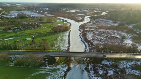vista aérea del tráfico que conduce sobre un puente sobre un río congelado durante el amanecer