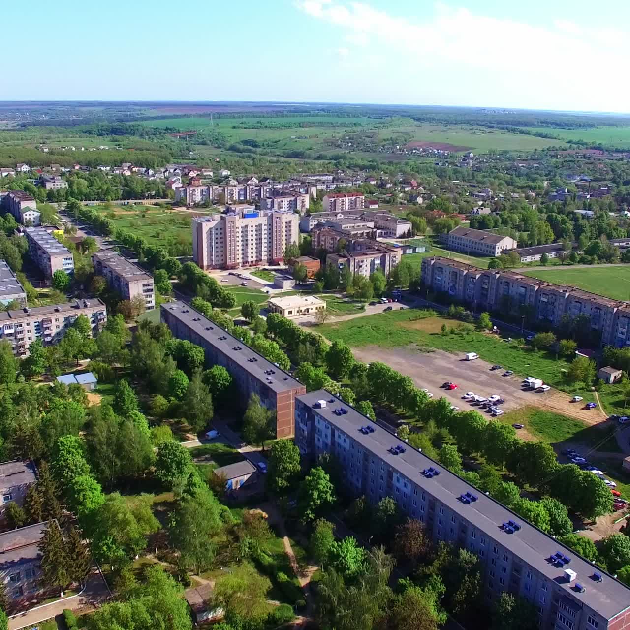 Cityscape with numerous blocks of flats. Picture of beautiful green town with rural outskirts. Aerial view