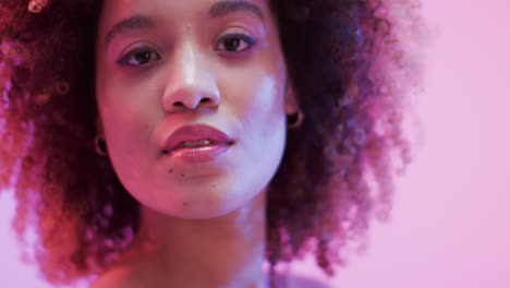 mujer biracial con cabello oscuro en luz azul y rosa, cámara lenta