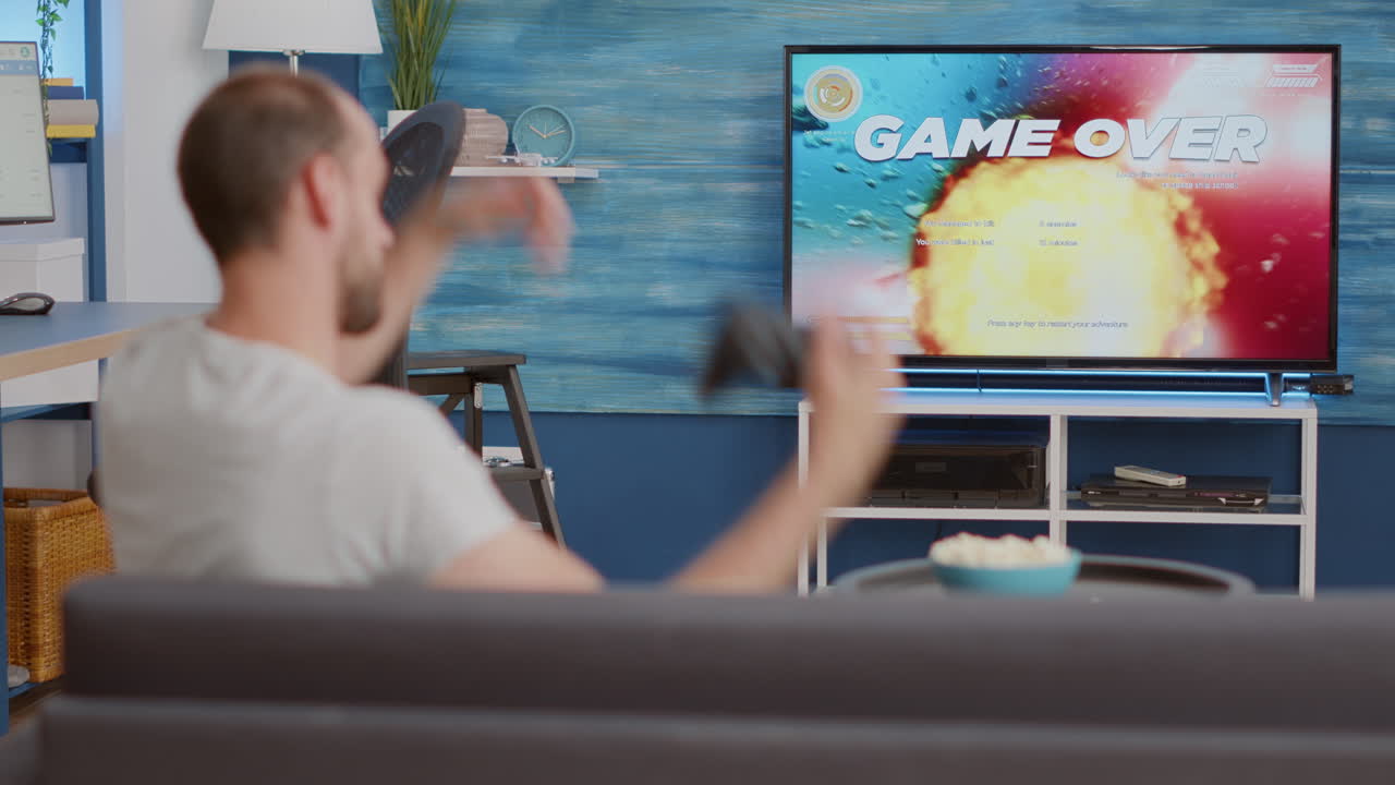 Man holding controller playing action space shooter on console disappointed because losing online game