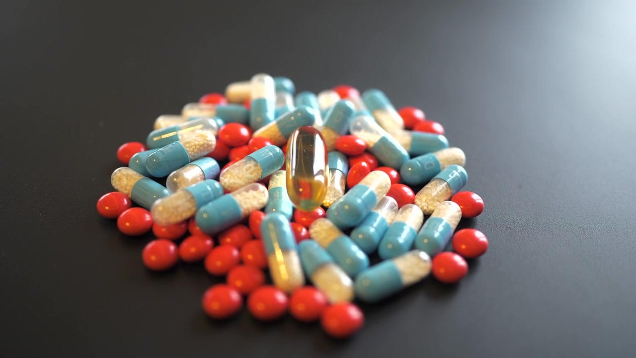 Pila di pillole e capsule mediche assortite su superficie scura