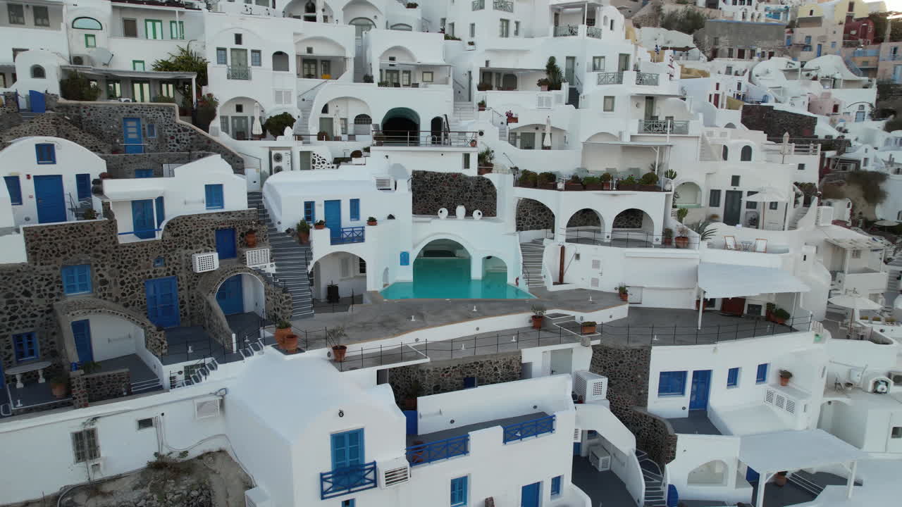 fotografía de aviones no tripulados de villas y apartamentos de lujo en la isla de santorini, grecia, fachadas blancas, puertas azules y piscina
