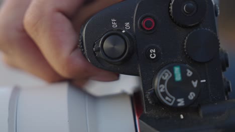 close up view: finger switches mirrorless digital camera off to on