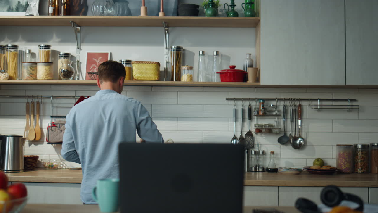 un hombre bailando cocinando solo en la cocina con una computadora portátil. un chef preparando el desayuno.