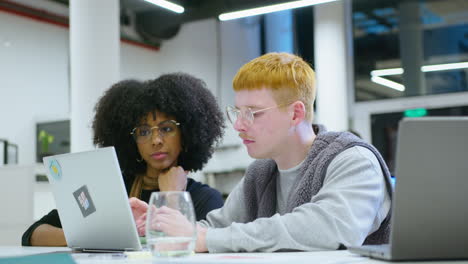 gen z coworkers working on laptop and discussing project in the office