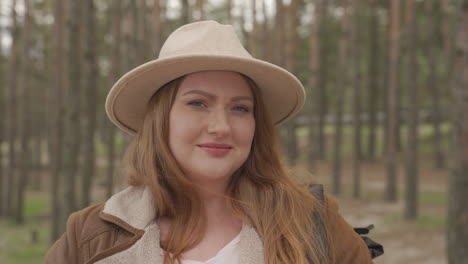 retrato de una hermosa mujer pelirroja con un sombrero de camello en el bosque