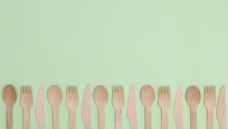 eco friendly zero waste kitchen utensils cutlery ordering on bottom of light green background. stop motion