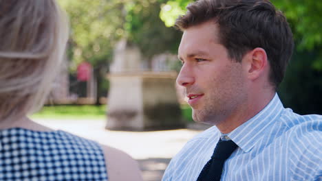 businessman talking to female colleague on break in park