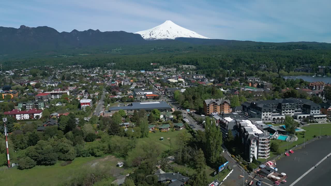 Descending Drone shot over Pucon with stunning view of the town, lake and Villarrica Volcano in the background on a clear day
