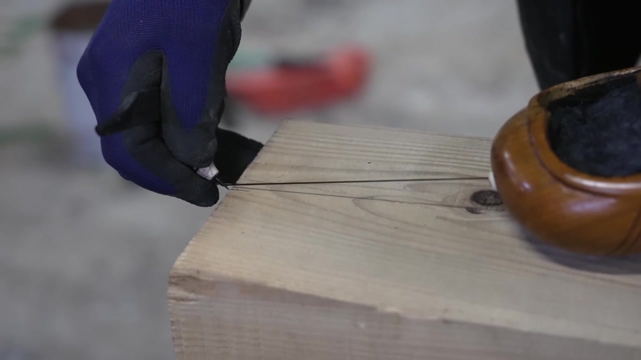 Carpenter snapping an inked marking line across a timber board using a traditional Japanese wooden ink pot