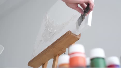 the artist applies a plaster base on a white canvas - the artist applies a plaster base on a white canvas. the artist works in his modern studio, modern abstract art