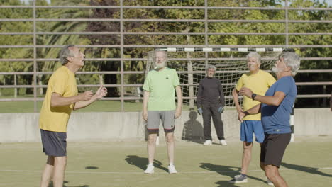 two senior sportsmen practicing skill of hitting ball with head while the team watching them in the stadium