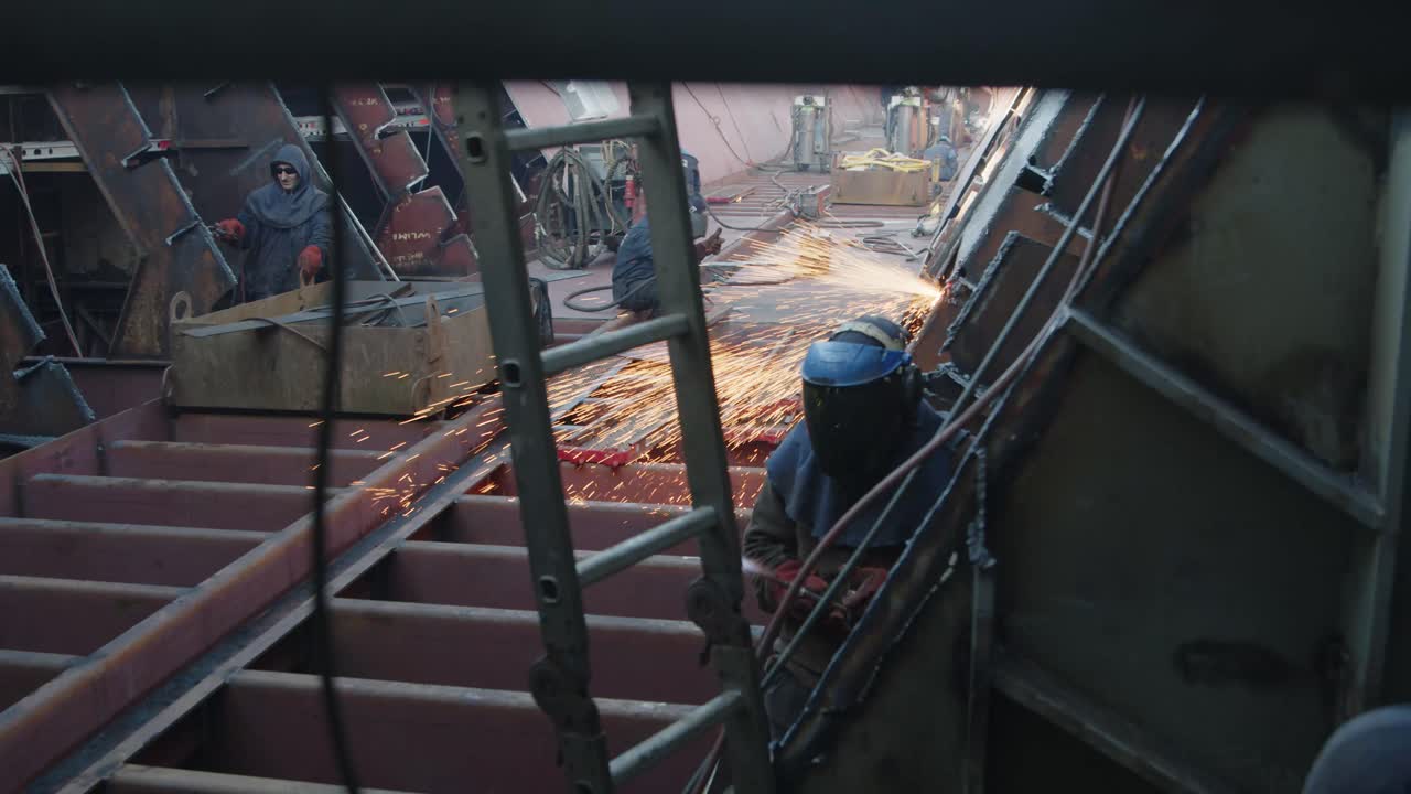 men in protective suits working on welding cargo ship in shipyard. loads sparks