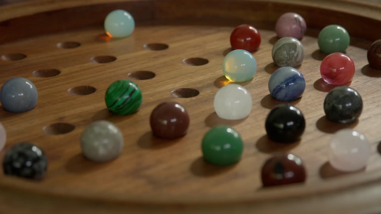 Medium close up of man playing an ornate wooden Solitaire table game. Clip 2