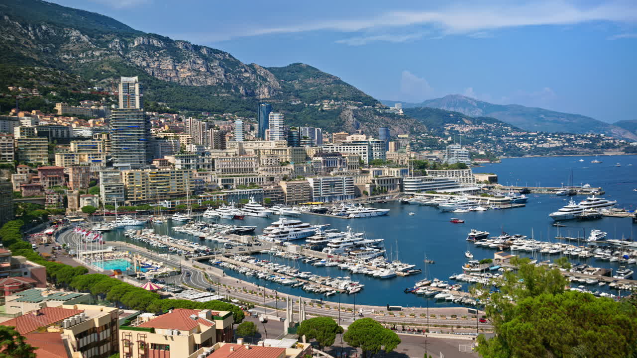 Aerial view of white boats docked in the Monaco Marina with the skyline on the background