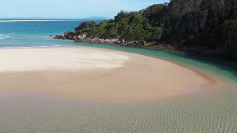 Revealing-drone-shot-of-wind-blowing-sand-across-a-sand-bar-at-Hat-Head-New-South-Wales,-Australia