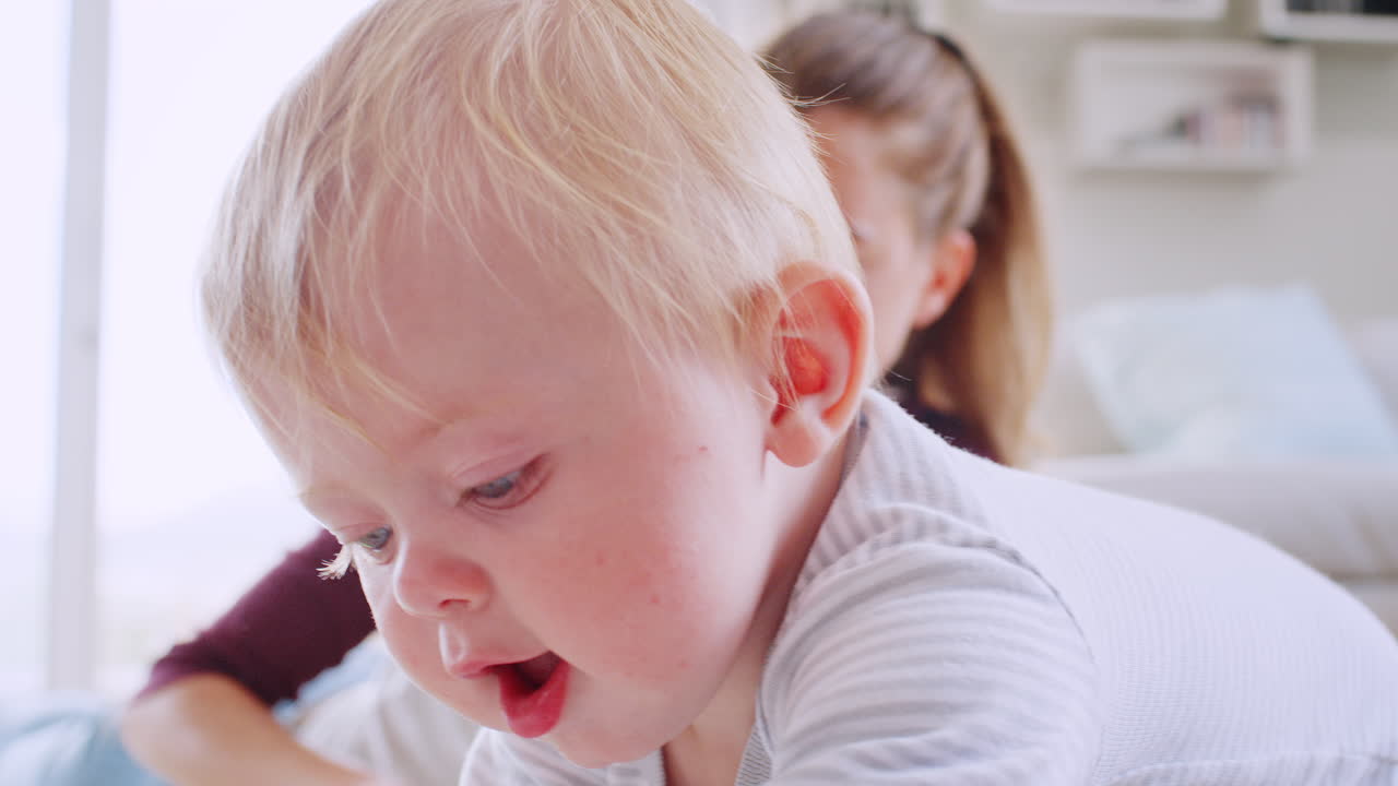 어린 엄마가 바닥에 누워서 어린 아들과 놀고 있다.