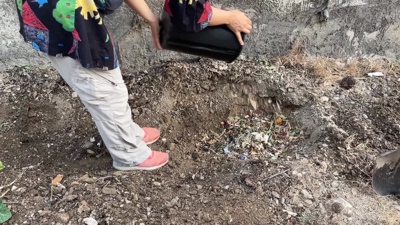 una joven hermosa en el patio trasero en teherán iran hacer procesamiento de compost en el jardín trasero naturaleza arrojar basura puede humedecer basura desechada en la excavación agujero en el suelo suelo en descomposición hacer fertilizante natural