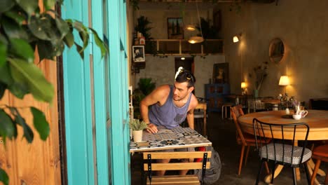 un turista caucásico quitándose la mochila antes de sentarse en la mesa de un café en nicosia