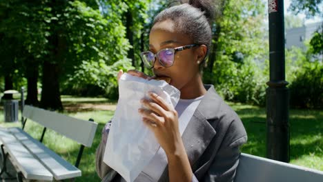 young woman eating a sandwich in a park