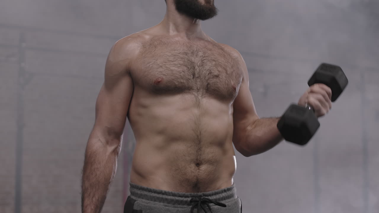 Sportsman Lifting Dumbbells in Gym