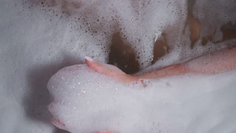 woman takes fluffy foam in bathtub closeup. playful lady enjoys cozy bath with soap froth in bathroom. woman rests caring of body and skin at home