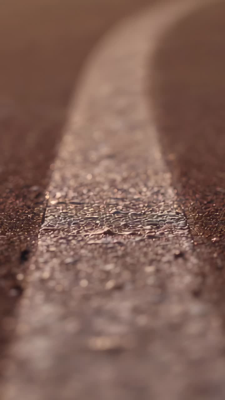 Video verticale: inizia con un primo piano, allarga l'inquadratura lungo la striscia dipinta, rivelando la texture e l'orizzonte
