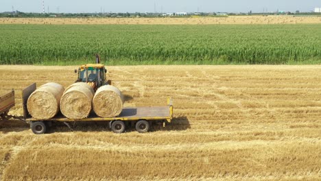 above view of agricultural field, collecting round bales of straw