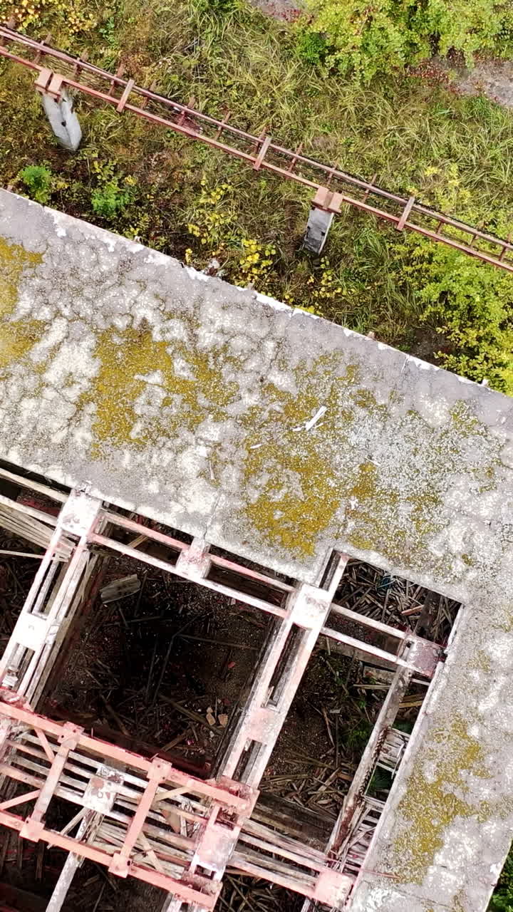 Destroyed building with holes in roof. Old abandoned building of industrial plant. Ruined warehouse. Top view.. Vertical video