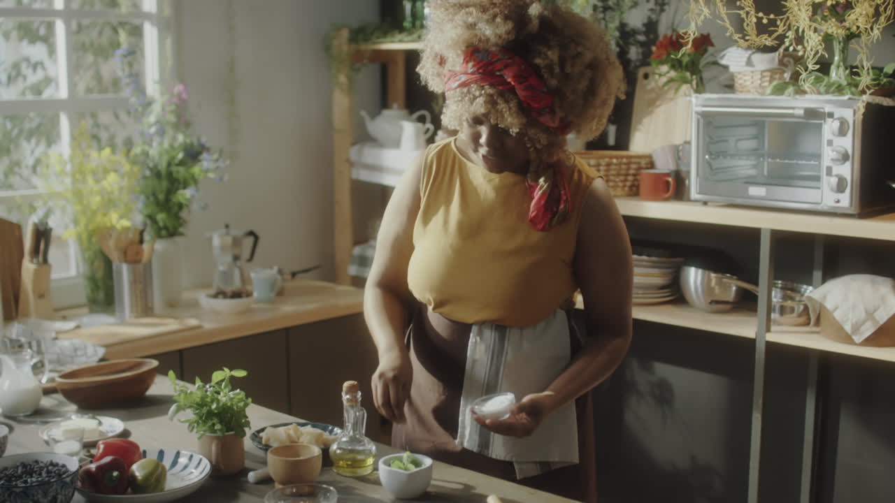 African American Woman Cooking and Preparing Food in a Bright Kitchen