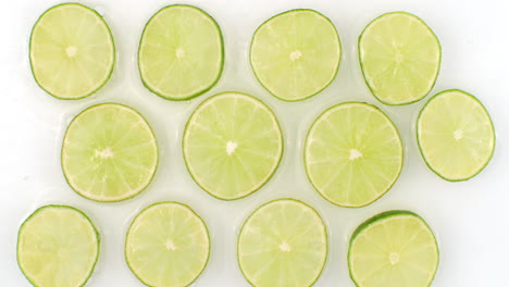 in slow motion water splashes pour water onto a beautiful juicy citrus many limes on a white background. vegetarian and fructorians.