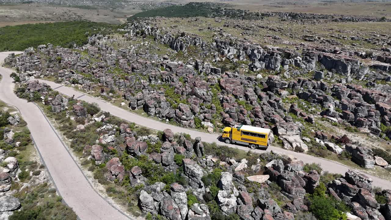 Drone footage of winding mountain road leading to Tundavala Gap, Angola, surrounded by rocky plateau and vast highland landscape in bright daylight