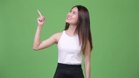 young beautiful asian businesswoman thinking while pointing up