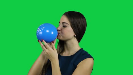 girl blowing up a balloon in front of a green screen