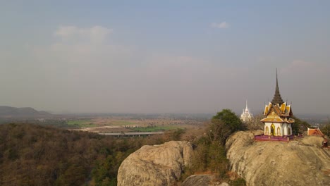 Panoramic-left-side-trucking-aerial-shot,-the-temple-of-merciful-god-with-the-trace-of-Buddha's-footprint,-Thai-Mondop-located-on-a-rock-mountain,-in-Wat-Phra-Phutthachai-in-Saraburi,-Thailand