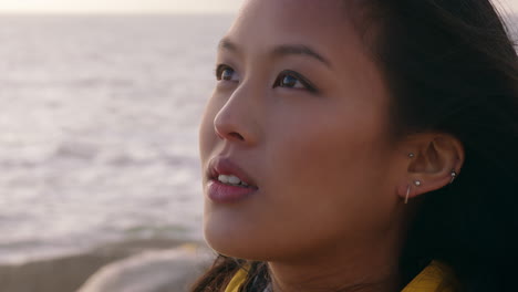 close up portrait beautiful asian woman enjoying freedom exploring wanderlust feeling relaxed on seaside contemplating spirituality at sunset with wind blowing hair