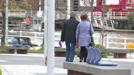 couple walking their dog in a city park by a river