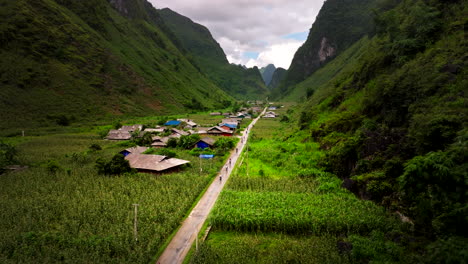 un grupo de motociclistas pasa por una aldea remota de hmong en yen min con campos de maíz.