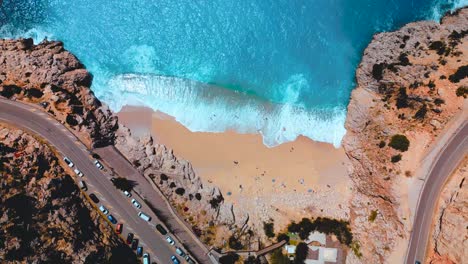 overhead drone footage of highways winding alongside an idyllic hawaiian beach, showcasing natural beauty of sandy shores and serene sea waves crashing shoreline during daytime