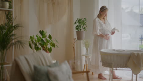 pregnant woman holding baby toy near crib
