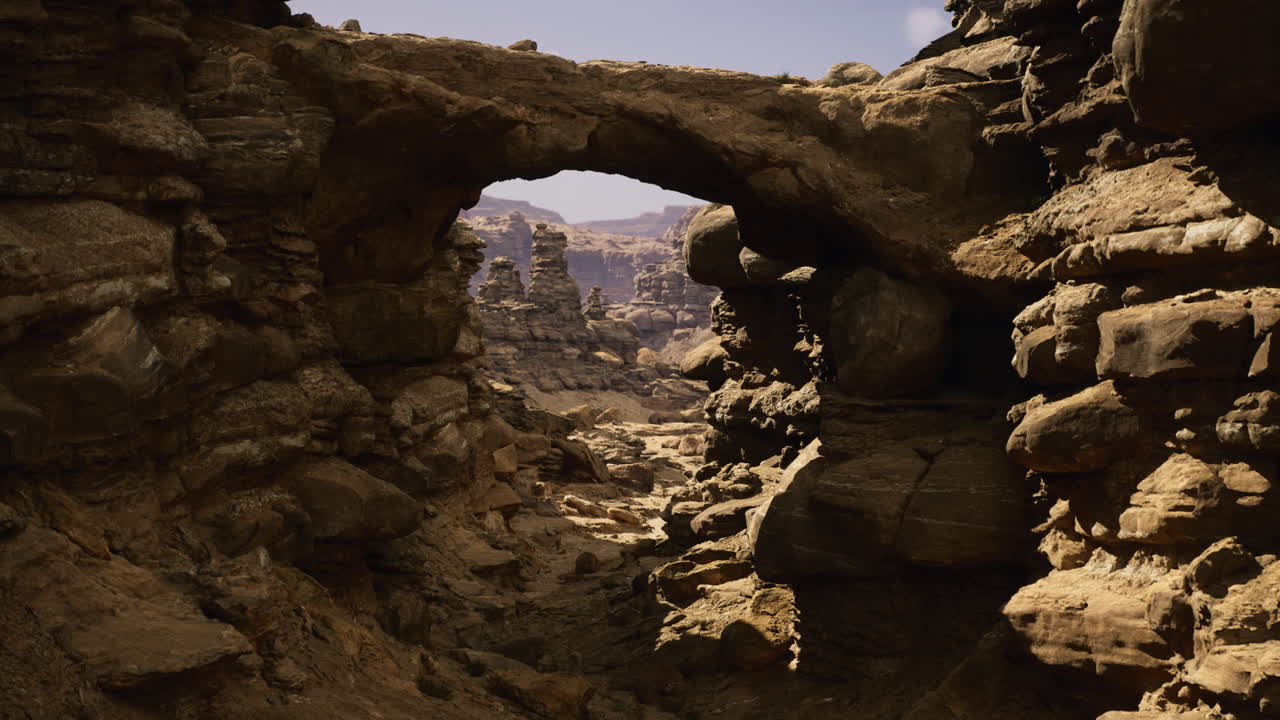 Rock formations create a natural bridge in a rugged canyon landscape
