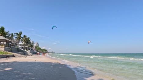 kite surfers glide over waves under clear skies.