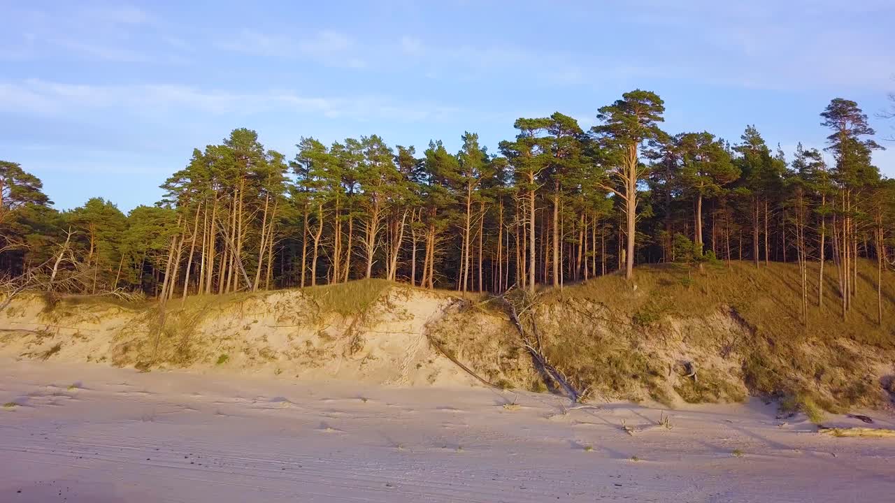 Wunderschöne einleitende Luftaufnahme der Ostseeküste an einem sonnigen Abend zur goldenen Stunde, mit weißem Sandstrand, Küstenerosion und Klimawandel, eine aufsteigende Weitwinkel-Drohnenaufnahme, die sich vorwärts bewegt.