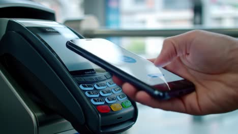 mobile payment technology: the future of transactions with contactless payment systems seen as a hand holds a smartphone above a payment terminal device