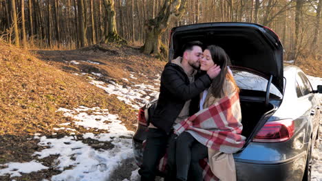 caucasian couple cuddling in a snowed forest.