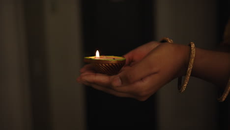 holding lit diya, person celebrating traditional indian festival with candle