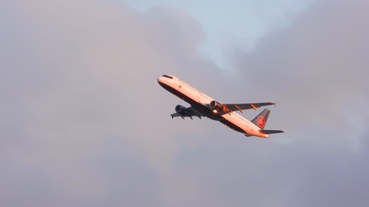 Airplane banking on takeoff at sunset with a partially cloudy sky