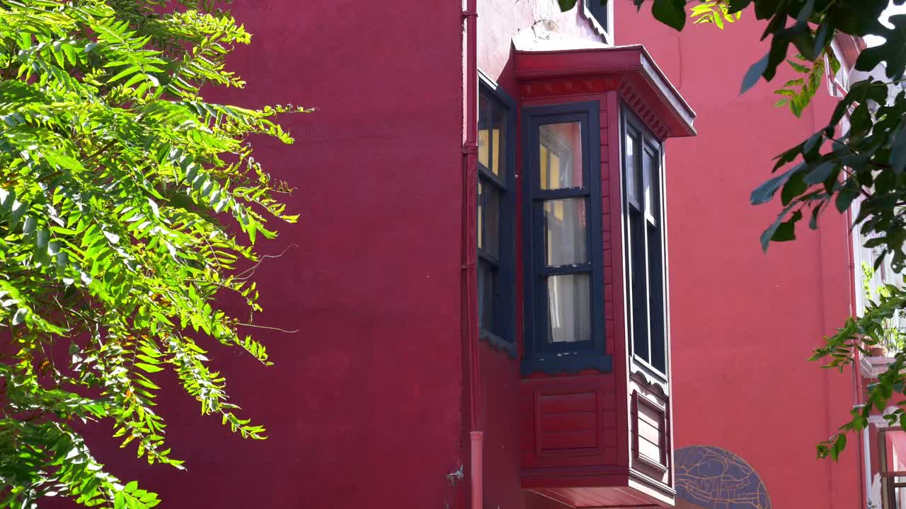 edificio rojo con ventana de bahía ornamentada y árboles