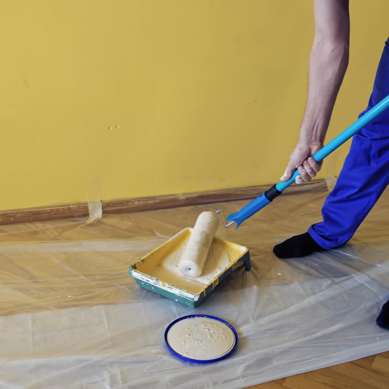 Worker get paint on a roller paint before the renovation. Man taking new color on a paintbrush in a paint tray to decorate walls in the apartment